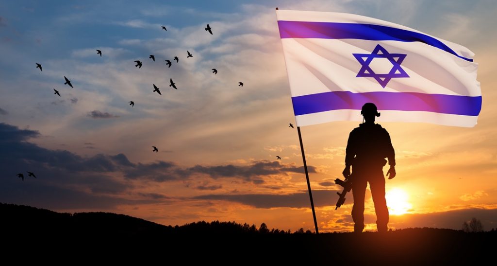 Soldat mit Israelflagge vor Abendhimmel